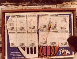 Campaña “Dele una mano a los desaparecidos", hojas-afiches de manos sobre muro urbano.