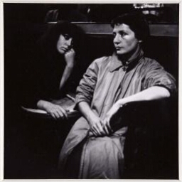 Vali Sitting in Cafe with Woman in Raincoat (Vali sentada en café con mujer con chubasquero)