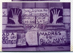 Manos gigantes pintadas en la pared y entre medio de ellas la consigna: "Sin justicia no hay democracia, devolución de los niños a sus hogares".
