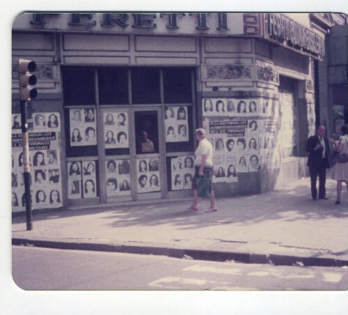 Muro y puertas de edificio Peretti cubierto de fotocopias con imágenes de mujeres desaparecidos